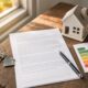 Tenancy paperwork, house keys, model house, and an EPC energy efficiency rating chart on a wooden table, representing the intersection of the Renters Rights Act and EPC obligations
